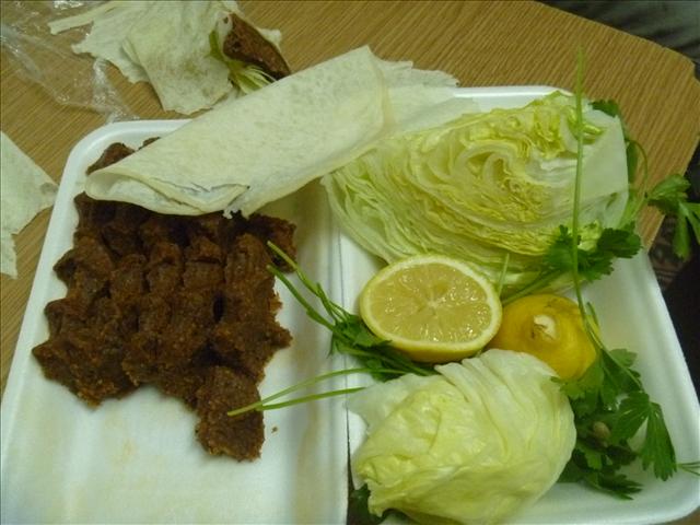 Çiğ Köfte zum Mitnehmen mit Salat, Zitrone, Petersilie und Granatapfelsoße. Die Köfte werden entweder in Salatblätter eingewickelt oder in dünnes Brot.